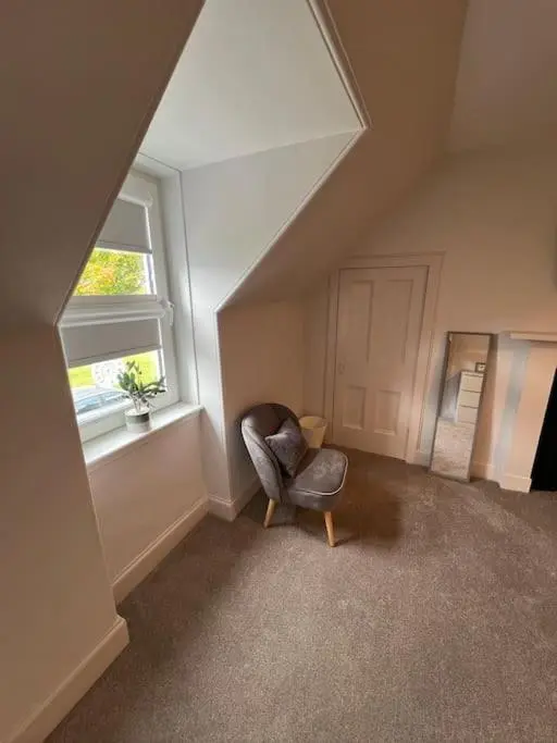 a chair sitting in a room with a window at 1 Links Place in Nairn