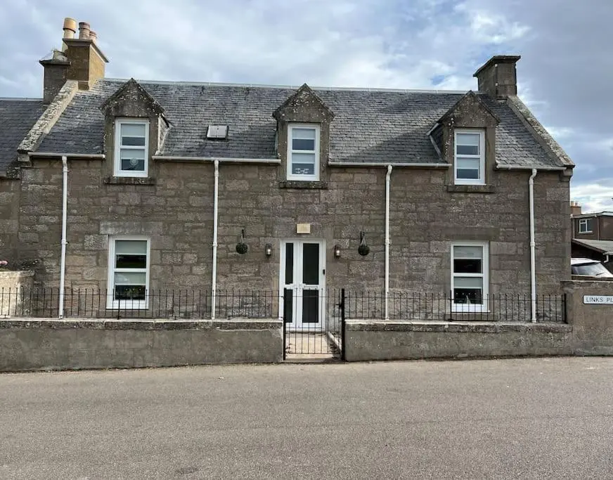 an old brick house with a white door at 1 Links Place in Nairn