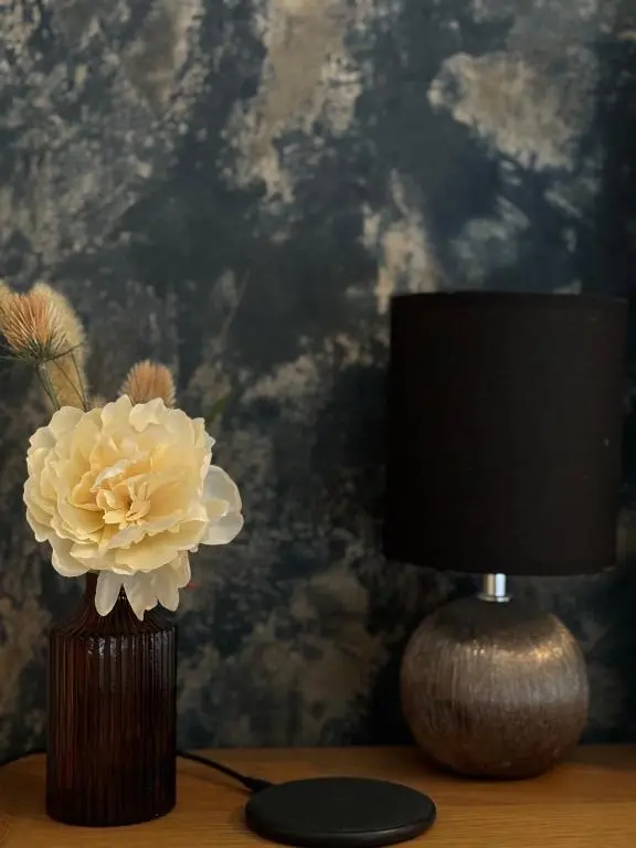 a lamp and a vase with a flower on a table at Ramsay Lane in Lossiemouth