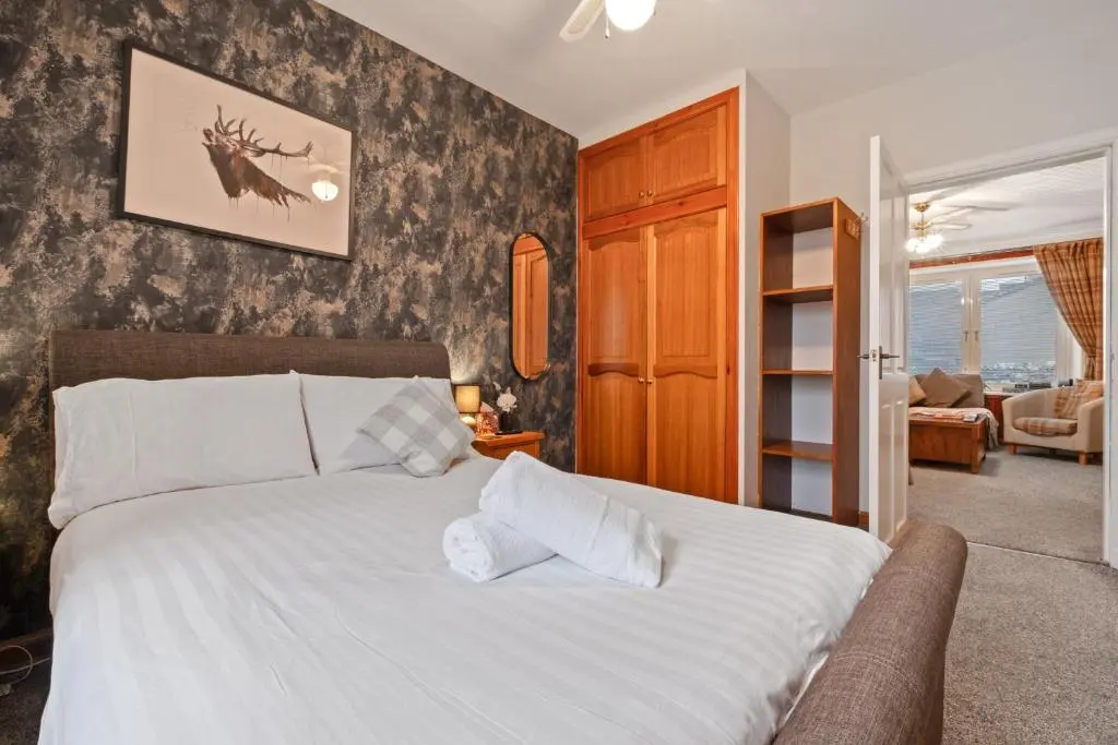 a bedroom with a white bed and a living room at Ramsay Lane in Lossiemouth