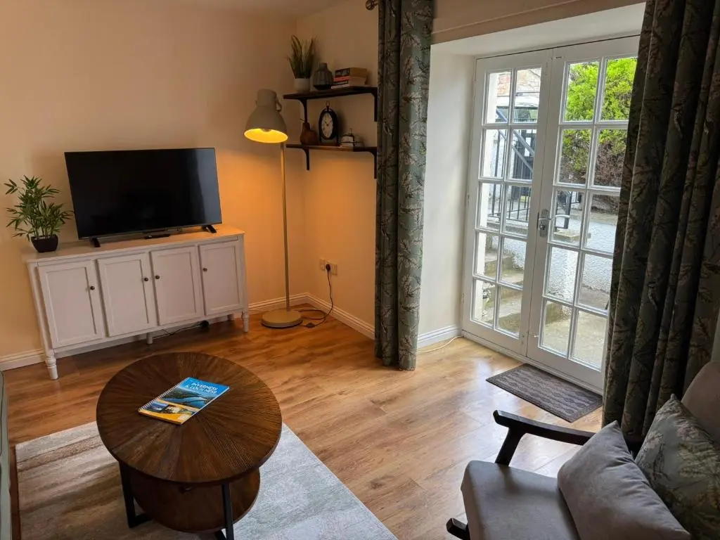 a living room with a television and a table at 20a, By The Ness in Inverness
