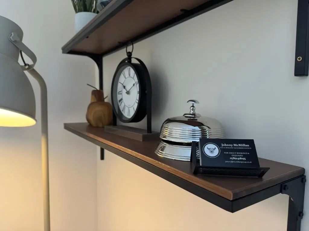 a shelf with a clock and a book on it at 20a, By The Ness in Inverness