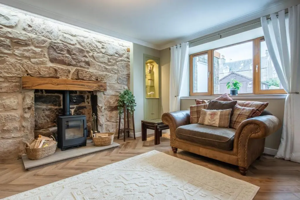 a living room with a stone fireplace and a chair at Mabels Cottage by the beach in Nairn