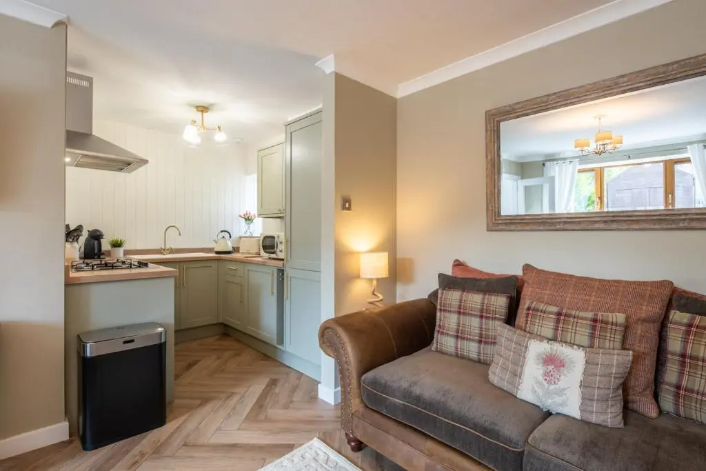 a living room with a couch and a kitchen at Mabels Cottage by the beach in Nairn
