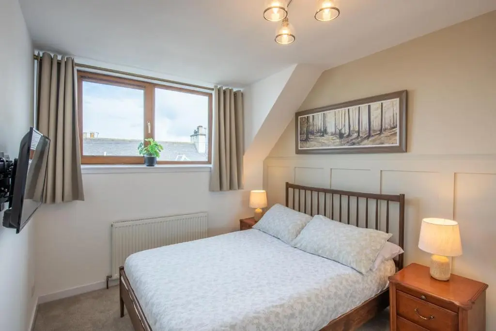 a bedroom with a bed and a window at Mabels Cottage by the beach in Nairn