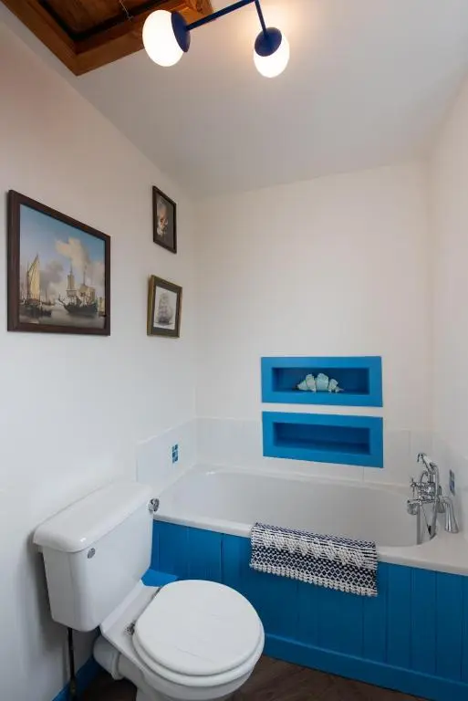 a bathroom with a toilet and a bath tub at Mabels Cottage by the beach in Nairn