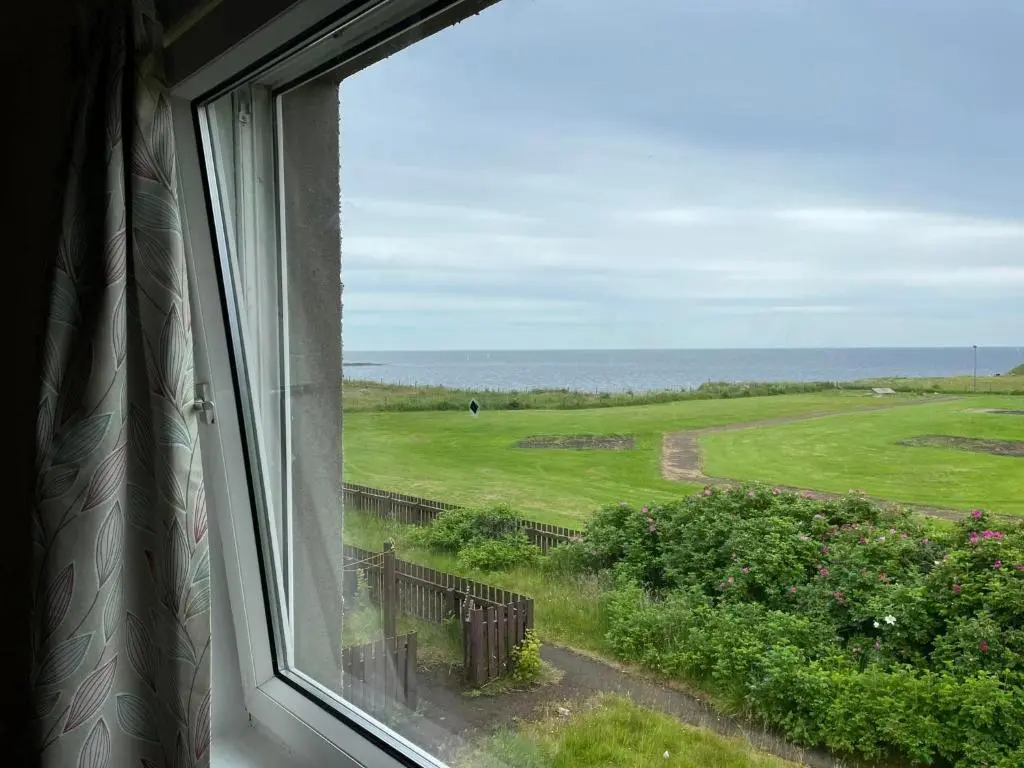 a window with a view of a golf course at Wick Bay Apartments in Wick