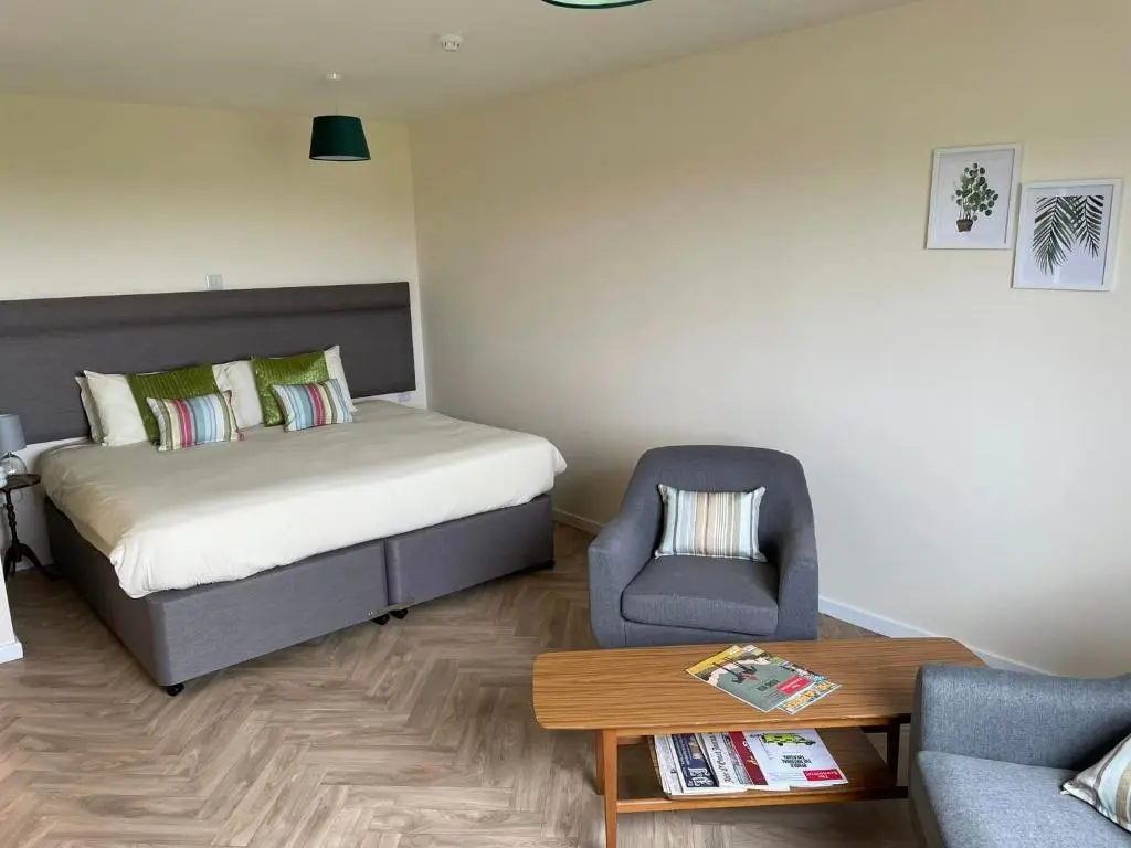 a bedroom with a bed and a chair and a table at Wick Bay Apartments in Wick