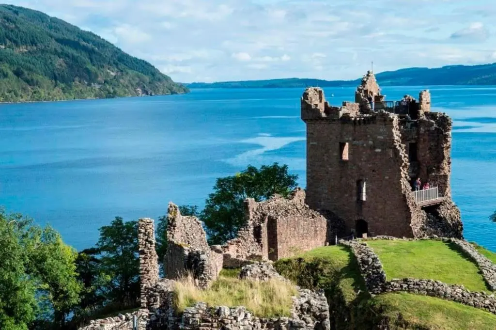 an old castle on the edge of a body of water at Fairvine Cabin Fort Augustus Mtn View Pet Friendly in Fort Augustus