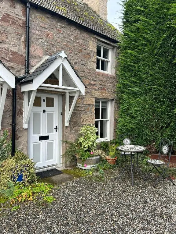 a stone house with a white door and a table at 1 Bedroom Alexander Snug-Free Parking in Inverness
