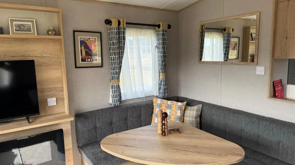 a living room with a table and a tv at Wildcat Lodge Grantown on Spey in Grantown on Spey