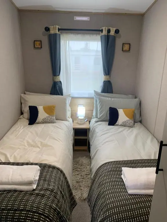 two beds in a small room with a window at Wildcat Lodge Grantown on Spey in Grantown on Spey