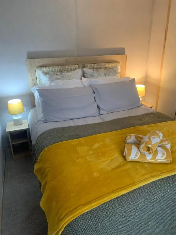 a bedroom with a large bed with a yellow blanket at Wildcat Lodge Grantown on Spey in Grantown on Spey