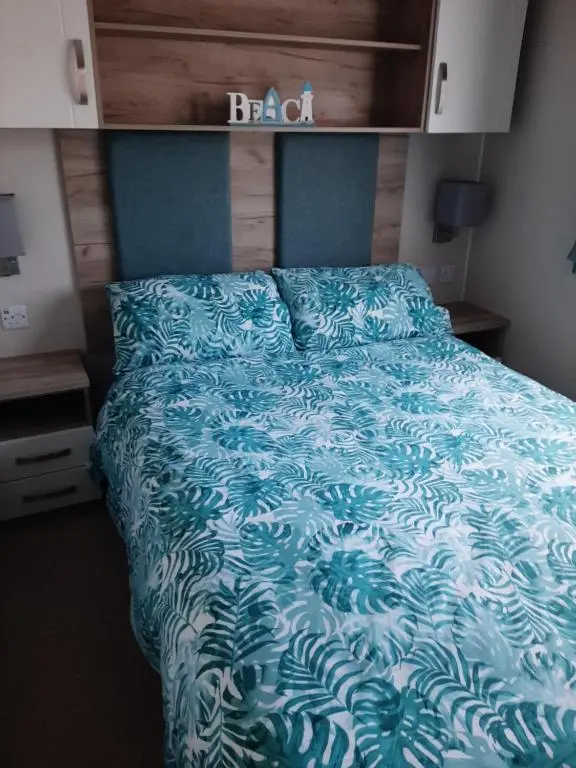 a bed with a blue comforter in a bedroom at Swallows at Silversands in Lossiemouth