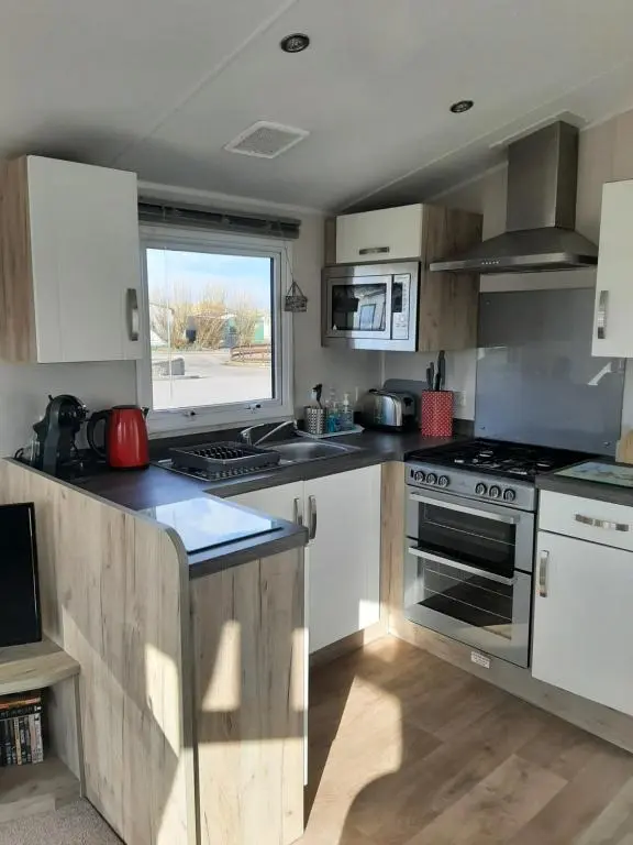 a kitchen with white cabinets and a stove top oven at Swallows at Silversands in Lossiemouth