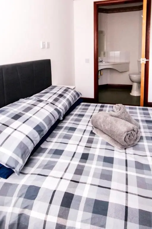 a bed with a checkered bedsheet and towels on it at Weston House in Keith