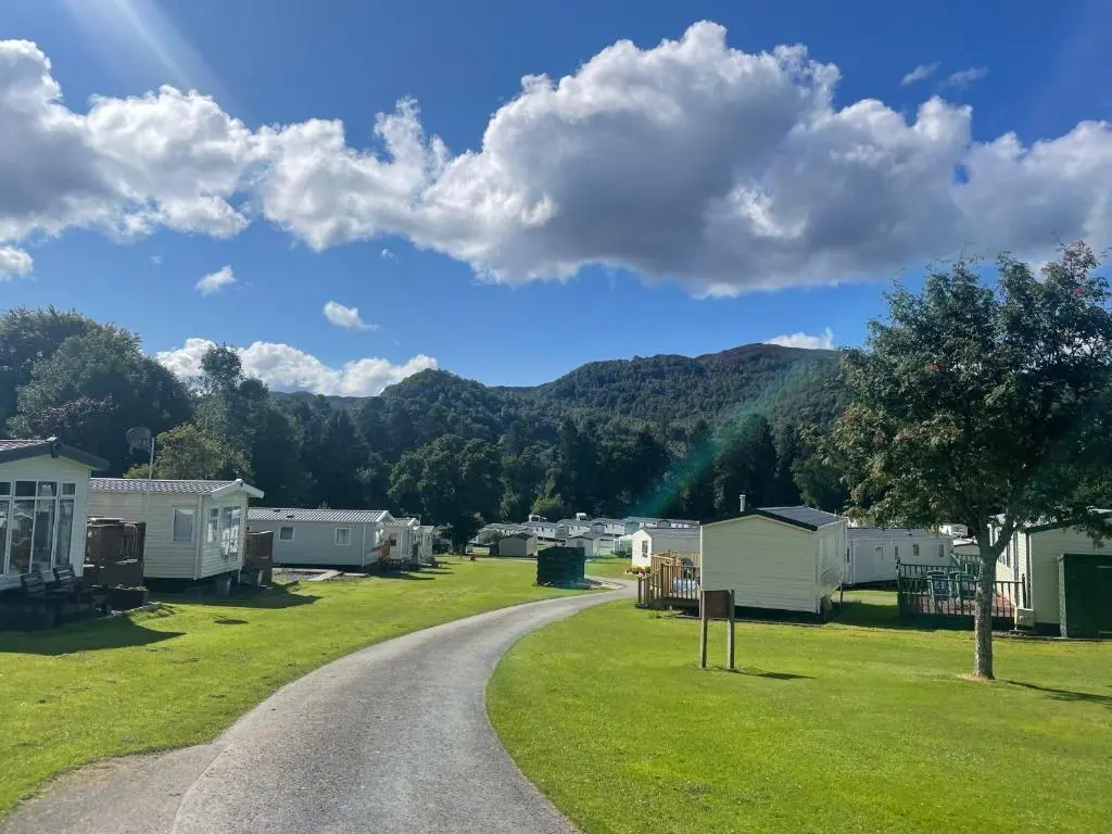a gravel road leading to a campsite with a mountain at Faskally Woods Holiday Park in Pitlochry