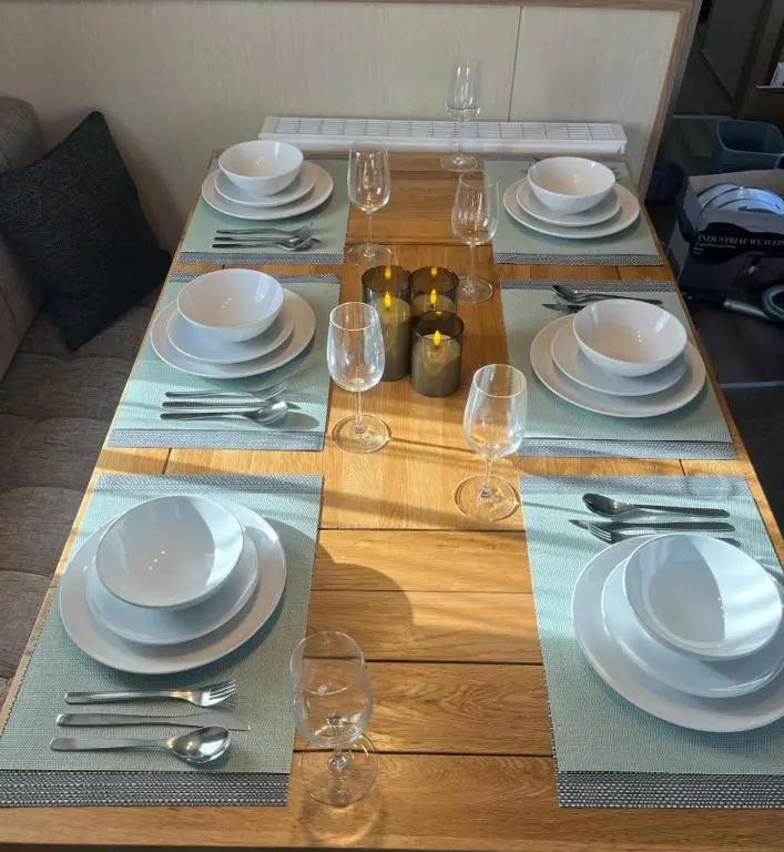 a wooden table with plates and wine glasses on it at The mountain retreat in Aviemore