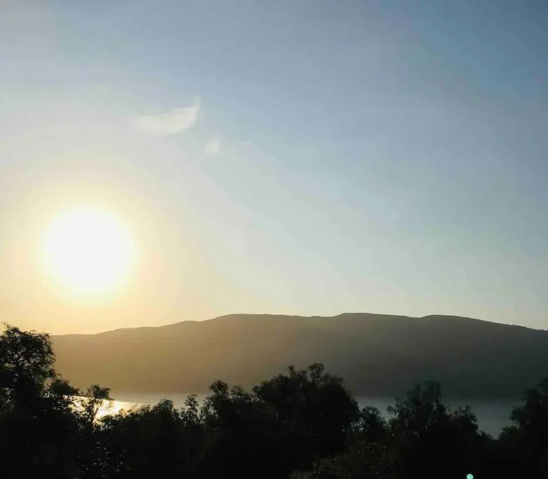 a sun setting over a foggy mountain with the sun rising at The Pod at Loch Ness Heights at Athbhinn, IV26TU in Inverness