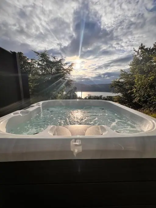 a jacuzzi tub with a view of the ocean at The Pod at Loch Ness Heights at Athbhinn, IV26TU in Inverness