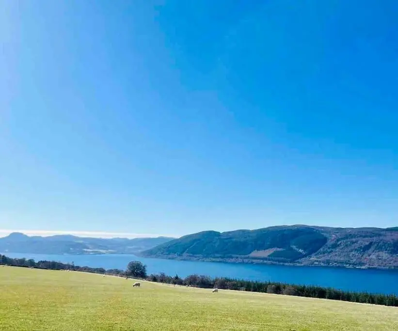 a green field with a lake in the background at The Pod at Loch Ness Heights at Athbhinn, IV26TU in Inverness
