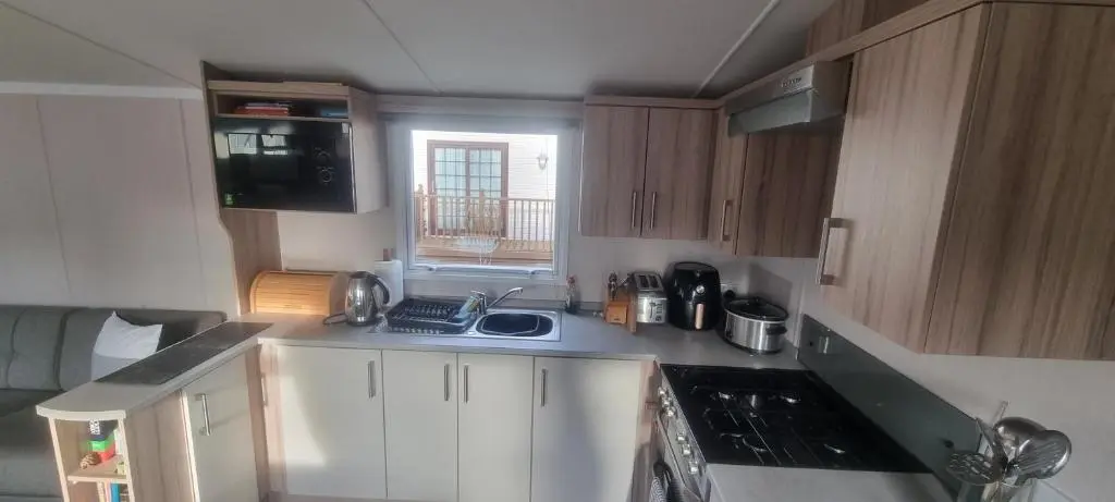 a kitchen with white cabinets and a sink and a window at swift LOIRE in Evanton