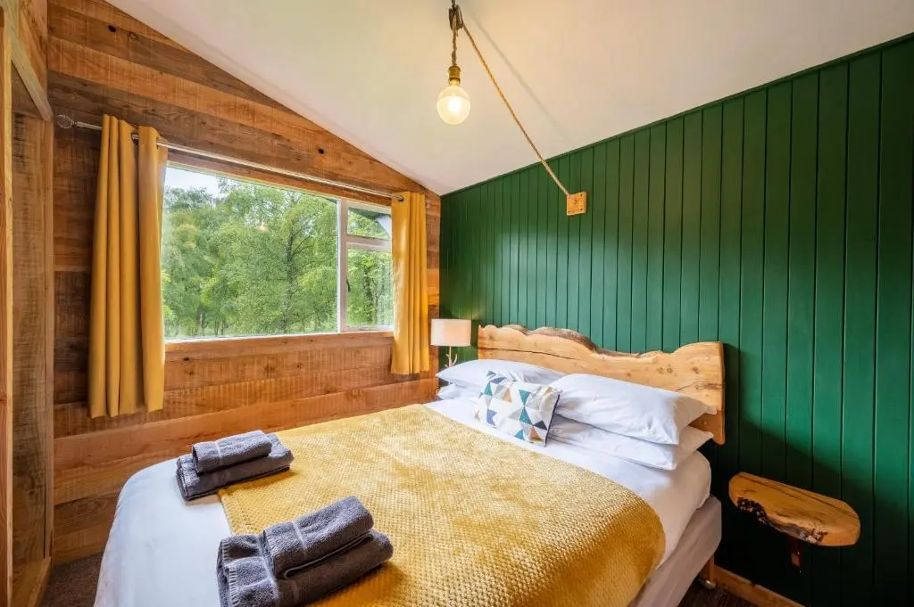 a bedroom with green walls and a bed with a window at Ancarraig Lodges in Drumnadrochit