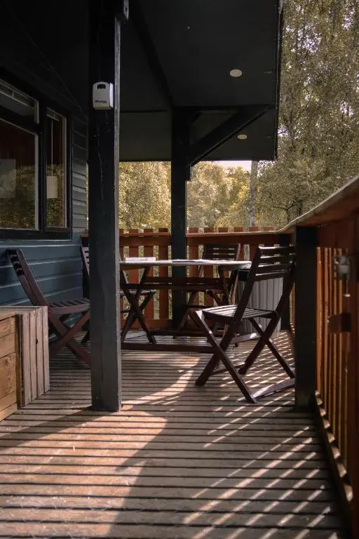 a deck with a table and chairs on a porch at Ancarraig Lodges in Drumnadrochit