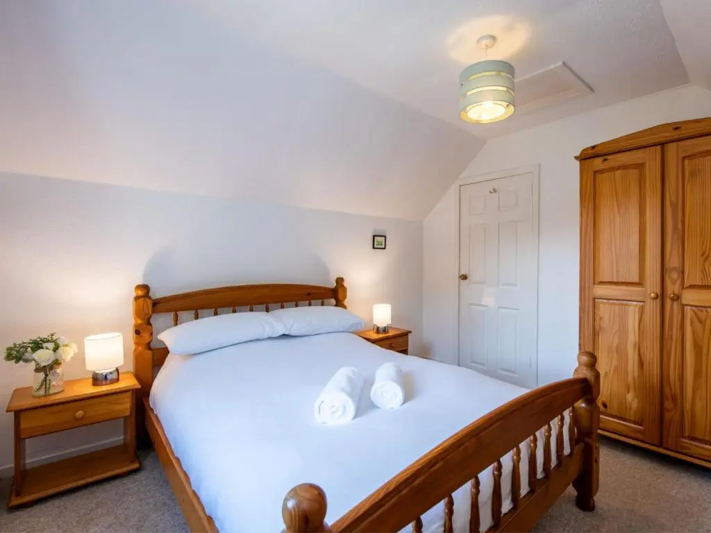 a bedroom with a wooden bed with two night stands at Holiday Home Jenkins Cottage by Interhome in Fort Augustus