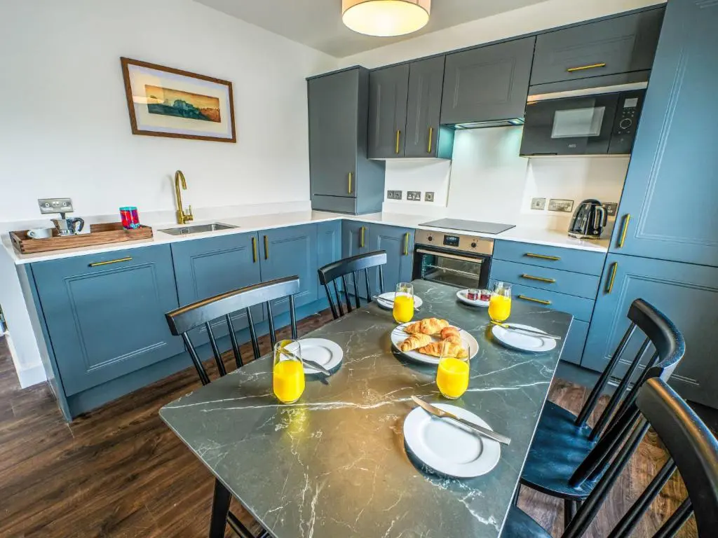 a kitchen with blue cabinets and a table with food on it at Apartment Craigmonie Apartment by Interhome in Drumnadrochit