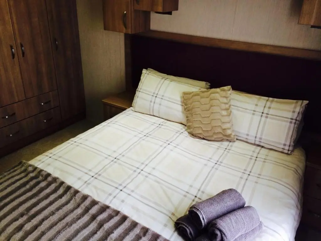 a bed with two pillows and two towels on it at Aviemore holiday park No 39 in Aviemore