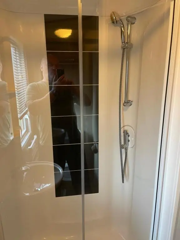 a man taking a picture of a shower in a bathroom at Aviemore holiday park No 39 in Aviemore