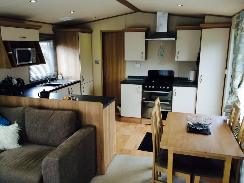 a kitchen and a living room with a couch and a table at Aviemore holiday park No 39 in Aviemore