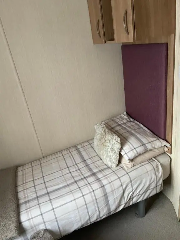 a small bed in a corner of a room at Aviemore holiday park No 39 in Aviemore