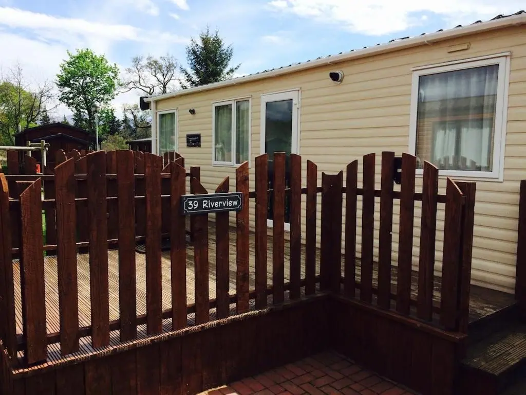 a wooden fence in front of a house at Aviemore holiday park No 39 in Aviemore