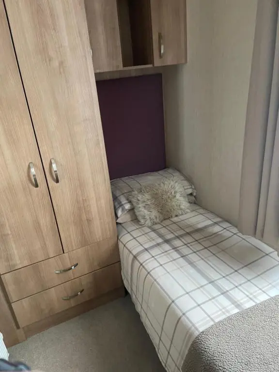 a small room with a small bed and a cabinet at Aviemore holiday park No 39 in Aviemore