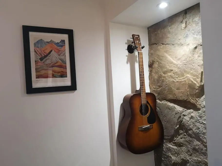 a guitar hanging on a wall in a room at Friars Shott Cottage in Inverness