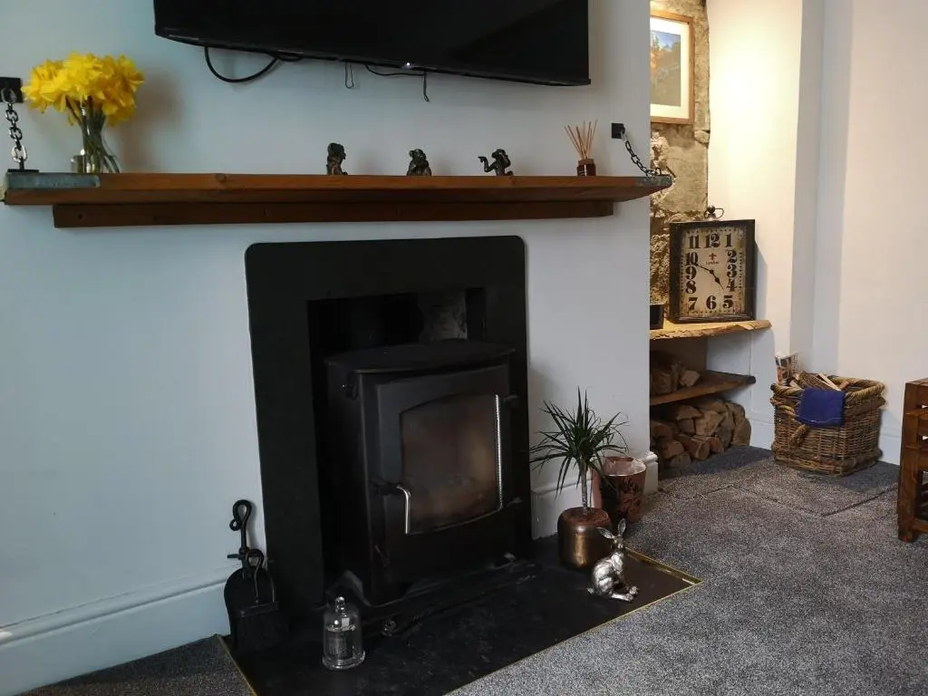 a living room with a fireplace with a television above it at Friars Shott Cottage in Inverness