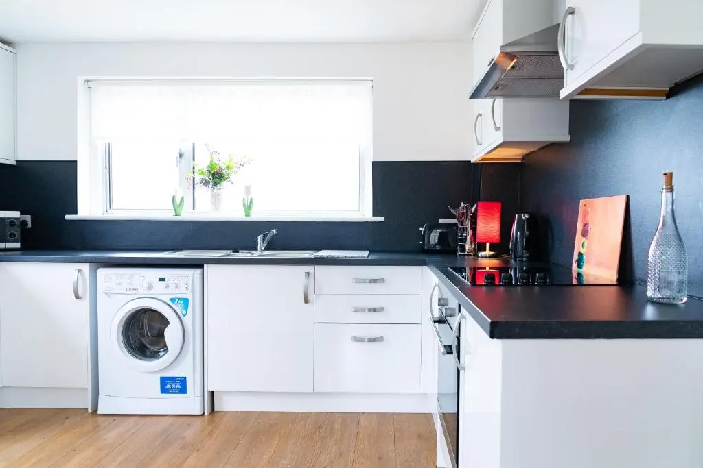 a kitchen with white cabinets and a washer and dryer at Carley's House, Macduff in Macduff