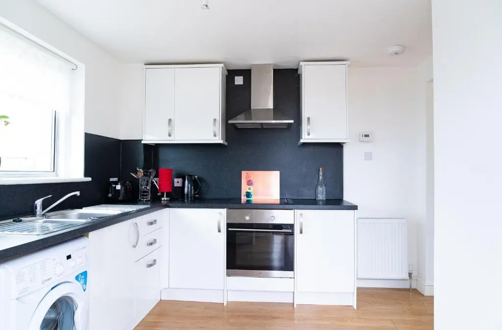 a kitchen with white cabinets and a dishwasher at Carley's House, Macduff in Macduff