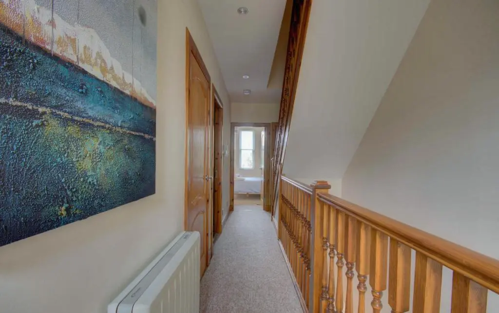 a hallway with a staircase with a painting on the wall at 1 Argyle Place, Dornoch in Dornoch