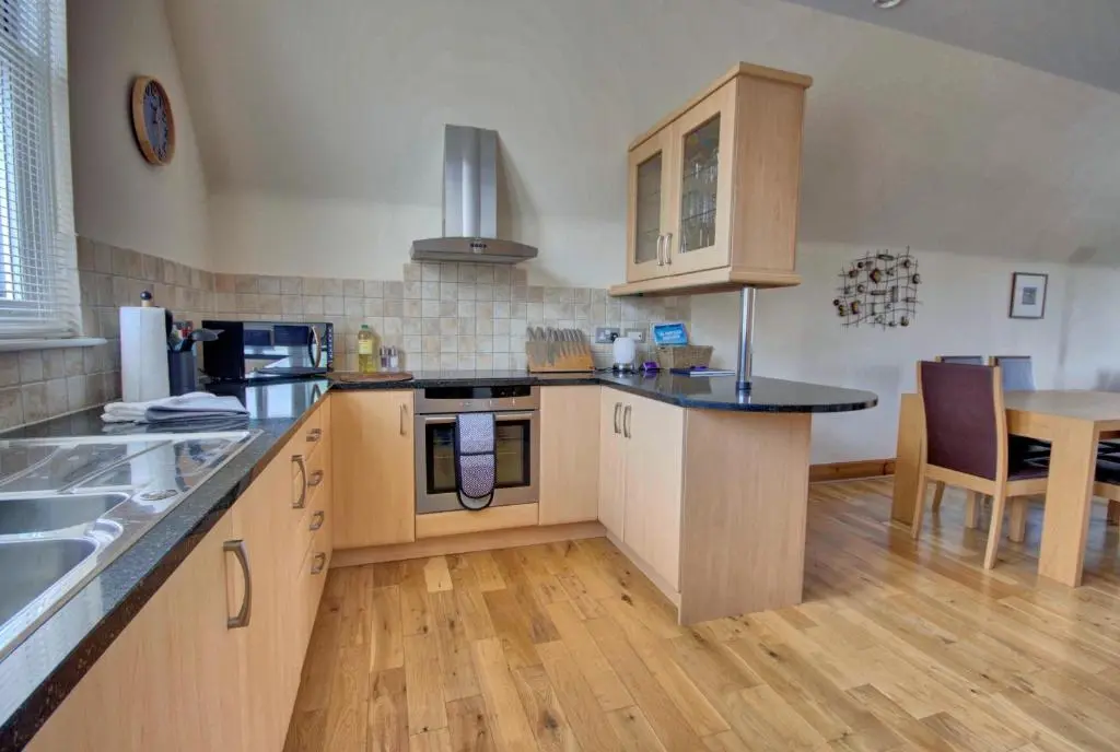a large kitchen with wooden cabinets and a table at 1 Argyle Place, Dornoch in Dornoch
