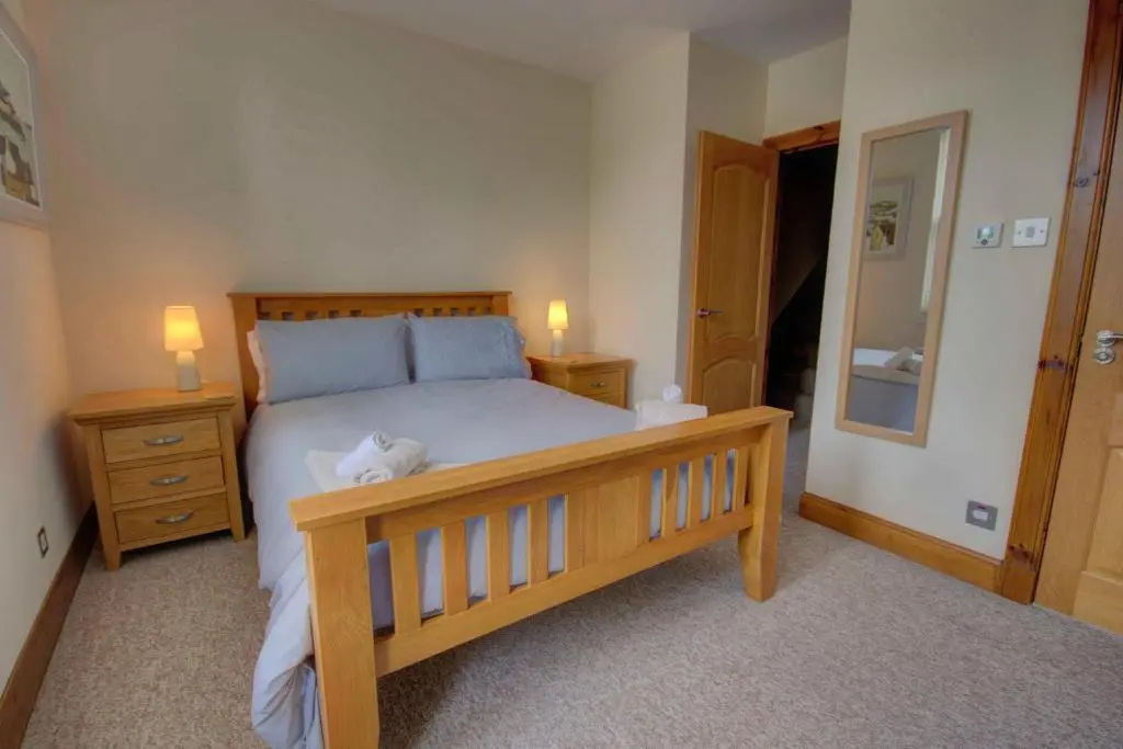 a bedroom with a wooden bed with two night stands and two lamps at 1 Argyle Place, Dornoch in Dornoch