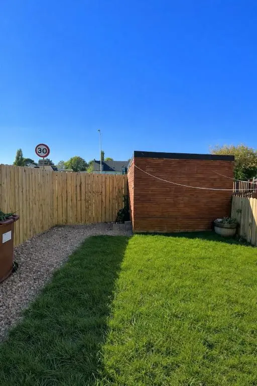a backyard with a wooden fence and green grass at Charlie's View in Inverness