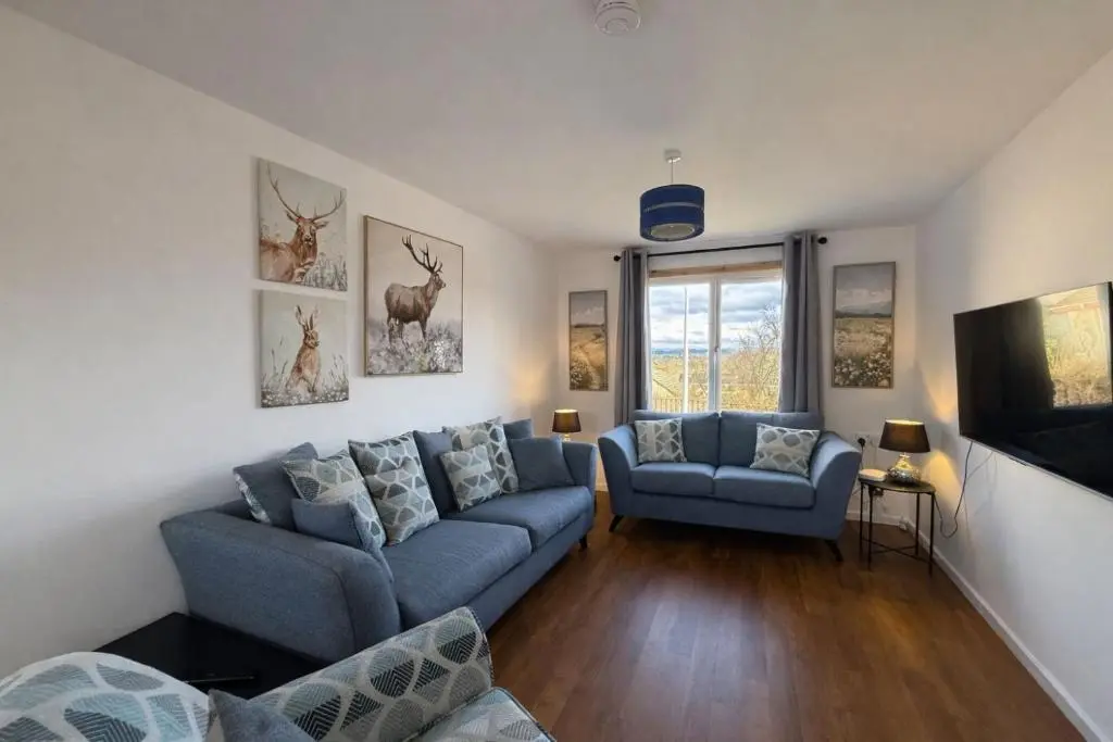 a living room with a blue couch and a tv at Charlie's View in Inverness