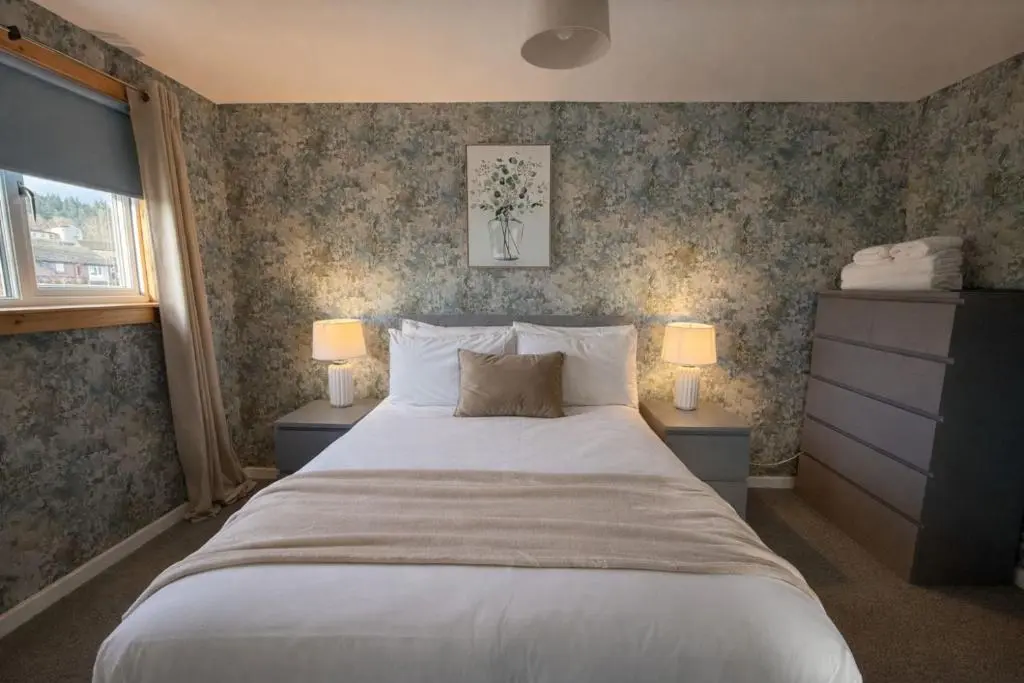 a bedroom with a large bed and two lamps at Charlie's View in Inverness