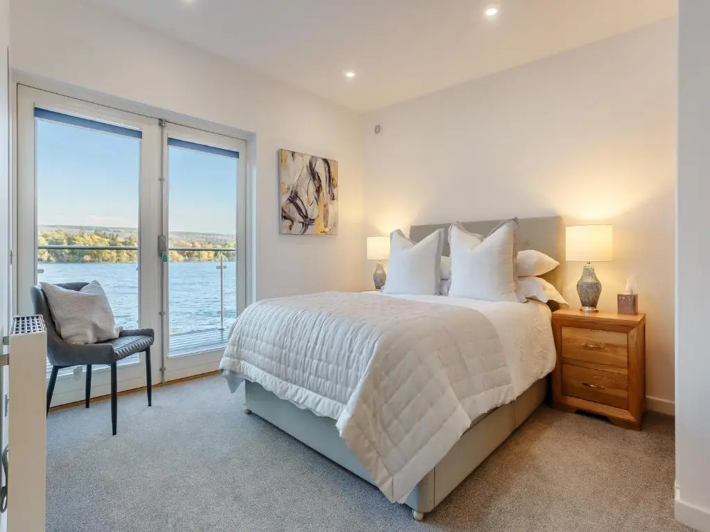 a bedroom with a bed with a view of the water at Kimcraigan Lodge in Lochend