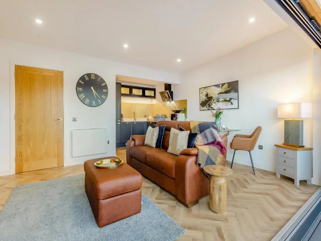 a living room with a couch and a clock on the wall at Kimcraigan Lodge in Lochend