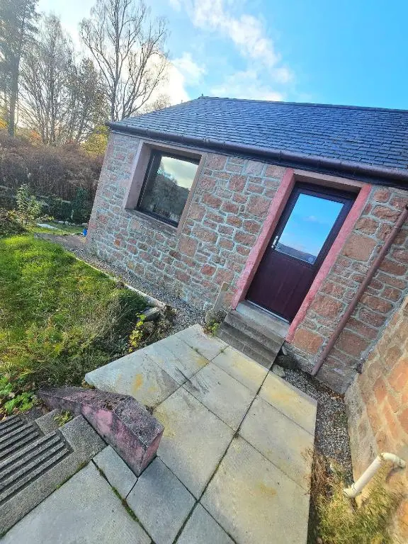 a brick house with a door and a window at Luichart Lodge in Lochluichart Station