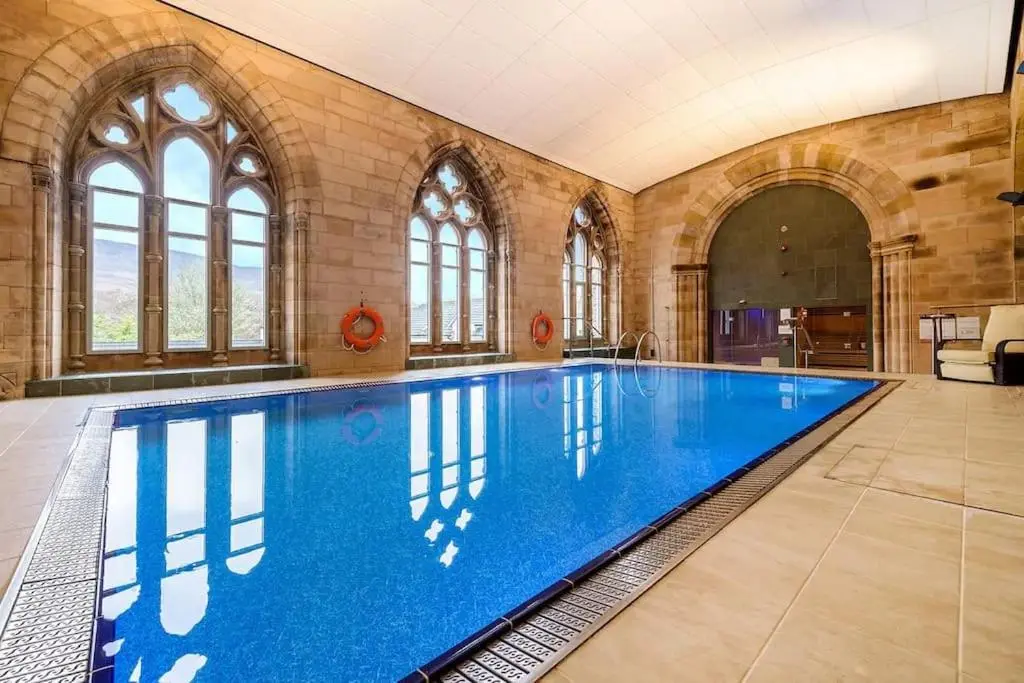 a large swimming pool in a large room with windows at Glen Mor in Fort Augustus